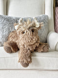 A plush highland cow stuffed animal with soft brown faux fur and crocheted accents.