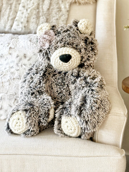 Plush teddy bear with textured fur sitting on a light-colored chair.