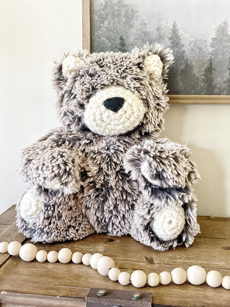 A plush bear stuffed animal made by ClaraLoo with brown faux fur and crocheted accents.