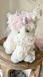 A plush unicorn stuffed animal made by ClaraLoo with crocheted accents.