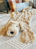 A plush puppy dog rug on the floor of a nursery. The puppy rug is made by ClaraLoo with soft tan colored faux fur.