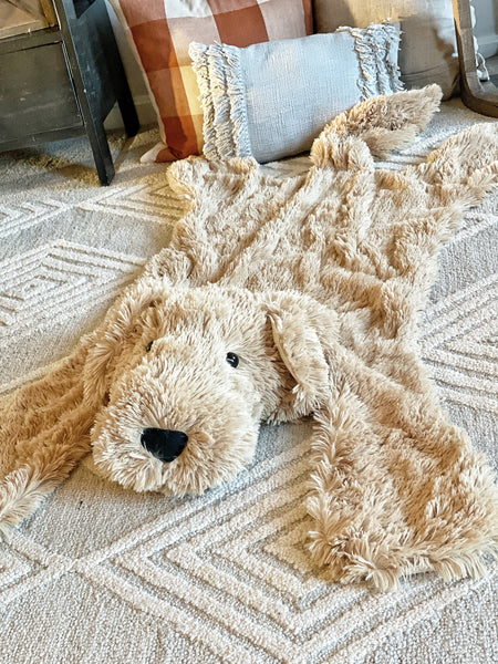 A plush puppy dog rug on the floor of a nursery. The puppy rug is made by ClaraLoo with soft tan colored faux fur.